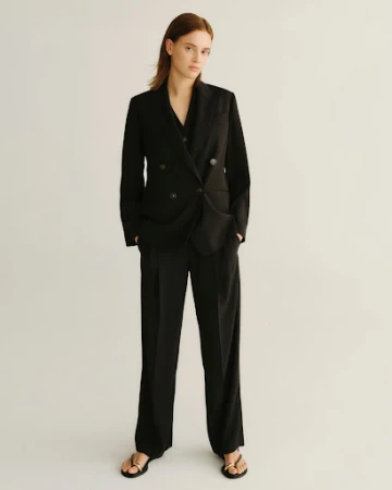 Model standing in a black double-breasted suit against a plain white background