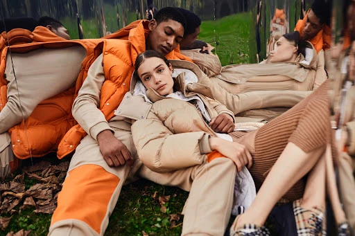 Two fashion models in outdoor fashion shoot, wearing puffer jackets and casual wear, surrounded by multiple reflections of themselves and the environment.