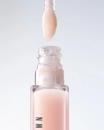 Close-up of lip gloss tube with wand applicator. The lip gloss is a light pink color, and the tube has a clear top and pink base.