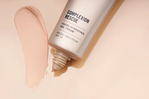Cosmetics tube and smear of tinted gel cream on a beige backdrop, product shot for beauty or skincare advertising, copy space.
