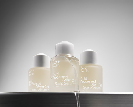 Three 'Act+Acre' bottles of Cold Processed Stem Cell Scalp Serum on a reflective surface with a gray gradient background. Beauty product.