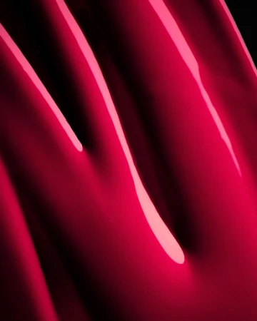 Macro shot of smooth glossy hot pink liquid cosmetic texture with sharp specular highlights
