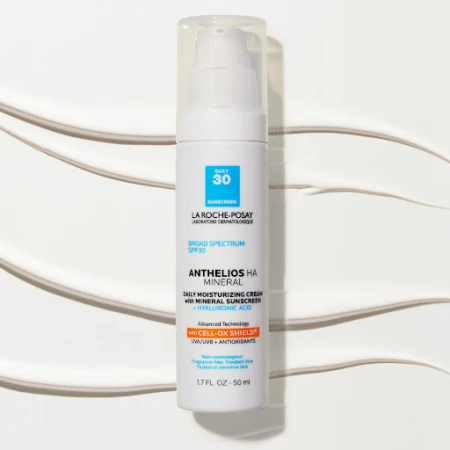 La Roche-Posay Anthelios HA Mineral sunscreen bottle with white pump dispenser on a white background with streaks of cream.