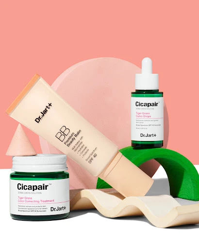 Dr. Jart+ skincare product assortment: BB cream, serum, and treatment cream on geometric props, against a peach and white background.