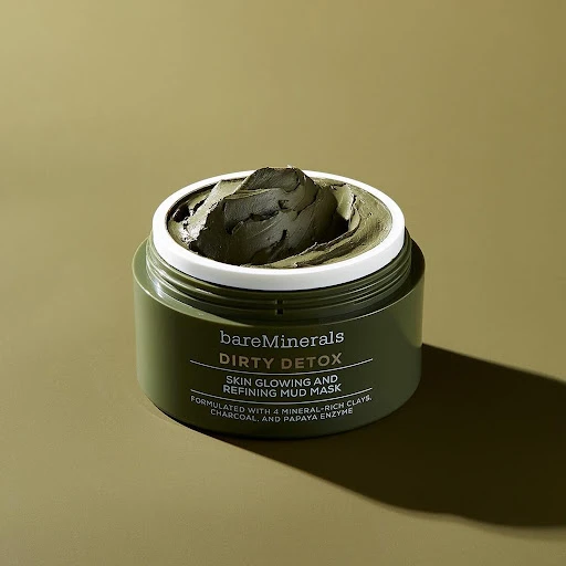 Close-up shot of a green bareMinerals Dirty Detox mud mask in its container, set against a matching green background, beauty product.