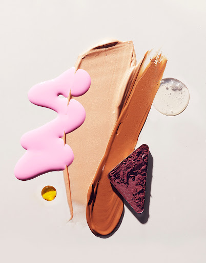 Abstract beauty product still life: Swatches of makeup foundation, eyeshadow, pink lip gloss and clear gel on a neutral background.