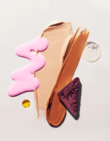 Abstract beauty product still life: Swatches of makeup foundation, eyeshadow, pink lip gloss and clear gel on a neutral background.