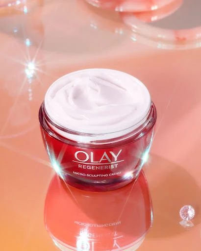Olay Regenerist Micro-Sculpting Cream jar on reflective surface, highlighting skincare product in a beauty or cosmetics context.