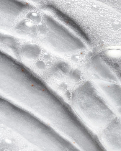 Close-up of a white textured surface with a pattern of ridges and valleys covered with a layer of transparent bubbles of varying sizes.