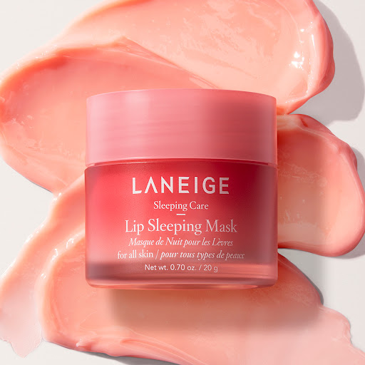 Close-up of a jar of Laneige Lip Sleeping Mask surrounded by smears of the pink product. The product is for all skin types.