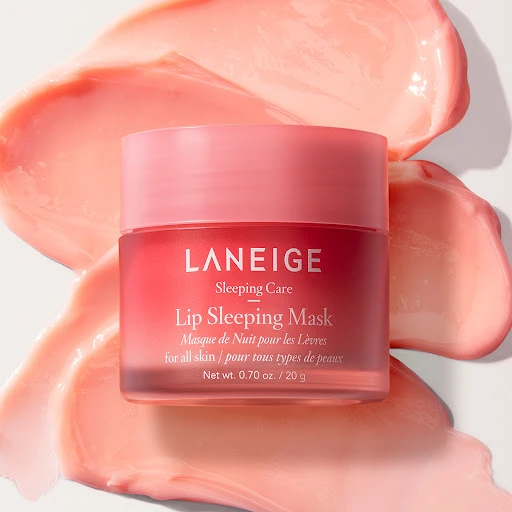 Close-up of a jar of Laneige Lip Sleeping Mask surrounded by smears of the pink product. The product is for all skin types.