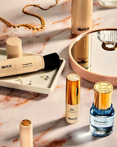 Still life shot of beauty and cosmetic products on a marble surface featuring lotion, perfume, and makeup applicators. Flat lay style.