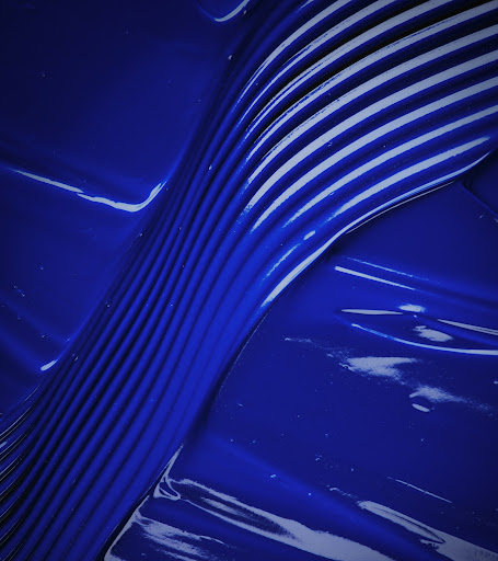 Abstract close-up of blue paint or liquid with textured, linear pattern and glossy finish creating a dynamic visual texture.