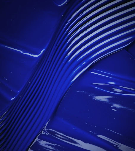 Abstract close-up of blue paint or liquid with textured, linear pattern and glossy finish creating a dynamic visual texture.