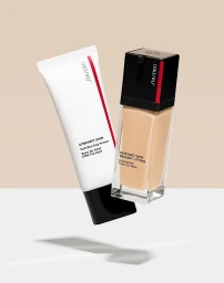 Shiseido foundation bottle and primer tube floating against a clean white and beige studio backdrop.