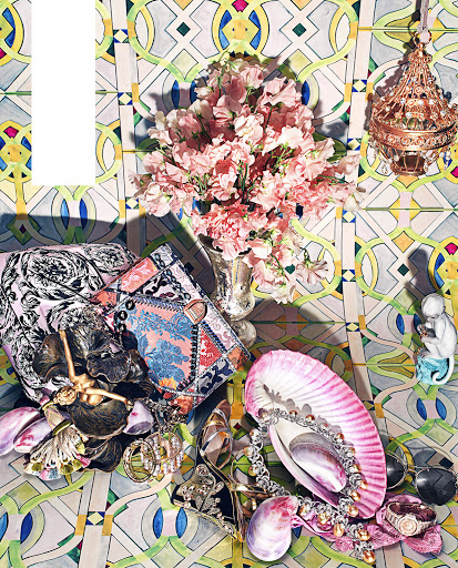 Still life of handbags, jewelry, flowers, and decorative objects against a colorful patterned wall, studio shot in soft lighting.