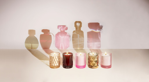 Five decorative candles displayed against a soft background, with shadow outlines of perfume bottles enhancing the product presentation.