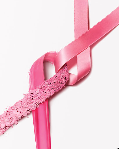 Still life featuring pink ribbon and crushed pink powder. The ribbon is looped and intersects with the powder, creating a visually striking image.
