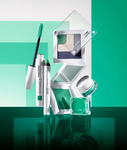 Cosmetic product still life with eye shadow, eye liner, mascara, skin cream and makeup palette against a color block background.
