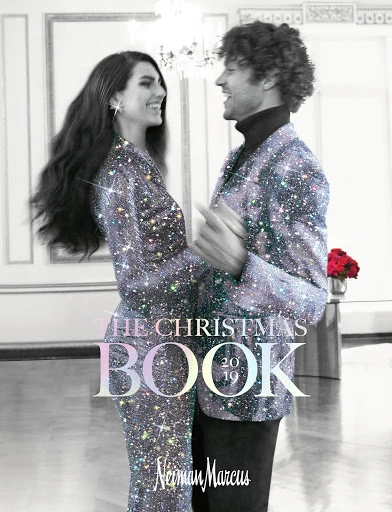 Magazine cover featuring a smiling couple in sparkling jackets dancing in a room with a chandelier, promoting a Christmas book from Neiman Marcus.