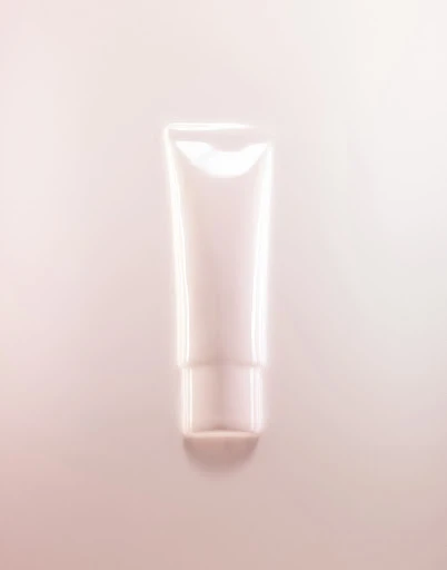 A cosmetic tube of cream or lotion is displayed against a light pink background, suitable for beauty, skincare, or product advertising.
