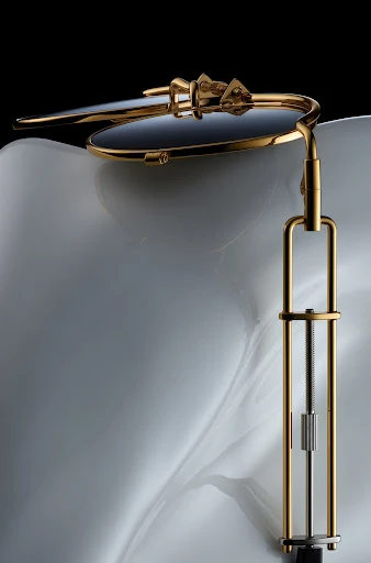 Dental tool with gold frame and adjustment mechanism on a white textured background, studio shot with black backdrop, high-quality image.