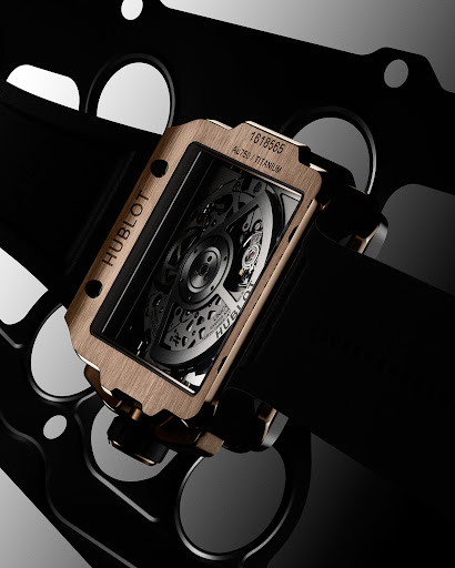 Hublot rectangular watch with a skeletonized dial and a gold and black band, showcased in a studio with dramatic lighting.