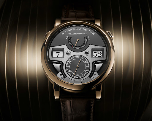 Close-up of an A. Lange & Söhne wristwatch with a dark gray face, gold casing, and a dark brown leather band, set against a striated background.