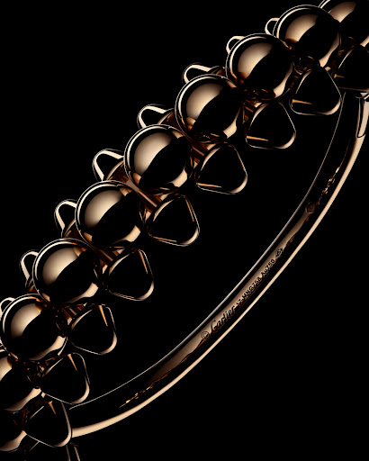 Close-up of a rose gold Cartier bracelet featuring flower-like shapes, set against a solid black background, with subtle studio lighting.