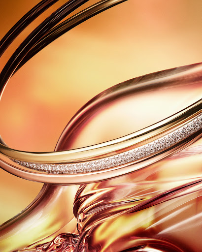 Abstract close-up of jewelry featuring swirling gold and rose gold bands encrusted with diamonds against a warm, golden background.