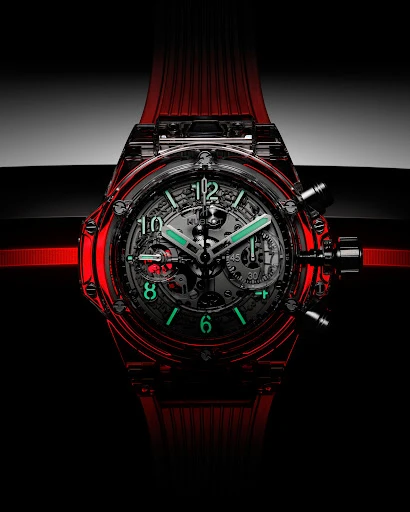 Close-up product shot of a luxury transparent red wristwatch with a skeleton dial against a dark background.
