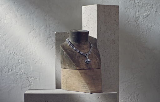 Elegant diamond necklace showcased on a mannequin against a textured wall backdrop, emphasizing craftsmanship and sophisticated design.