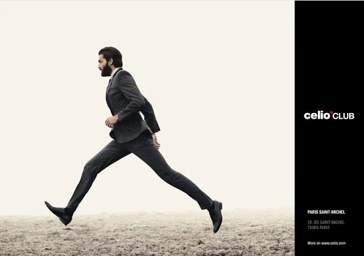 Man in suit leaps across a dirt field in a fashion advertisement, Celio Club logo on a black bar to the right side.
