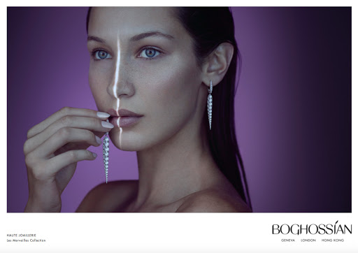 Close-up of a woman with pearl earrings and manicured nails, set against a gradient purple backdrop with stark vertical light.