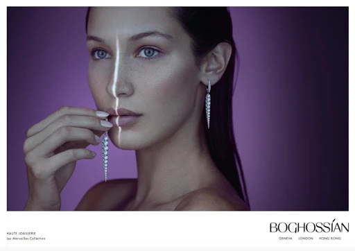 Close-up of a woman with pearl earrings and manicured nails, set against a gradient purple backdrop with stark vertical light.