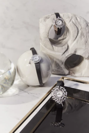 Elegant timepiece product shot. Wristwatches with black leather straps displayed on geometric white marble, marble background, studio lighting.