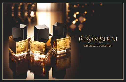 Three Yves Saint Laurent Oriental Collection fragrance bottles on a reflective surface against a black background with golden bokeh.