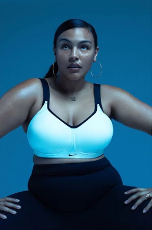 Woman wearing a white sports bra and black leggings against a solid blue studio backdrop