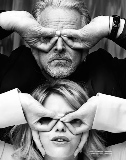 Black and white studio shot of a man and woman stacked vertically, each making circles around their eyes with their fingers.