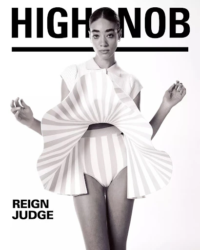 Fashion editorial featuring a model in a striped outfit against a white backdrop, with the text 'HIGHNOB' and 'REIGN JUDGE' visible.