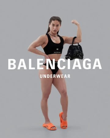 Muscular female model wearing black underwear and orange slides holding a black handbag against a grey backdrop