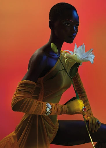 Elegant portrait of a Black woman in yellow dress, holding a white lily, set against a vibrant gradient backdrop, showcasing beauty and fashion.