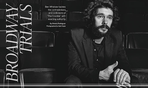 Monochrome portrait of Ben Whishaw in a theater, gazing pensively with a beard and dark hair, wearing a black jacket and shirt.