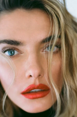 Close-up portrait of a woman with vibrant red lipstick, blue eyes, and blonde hair framing her face.