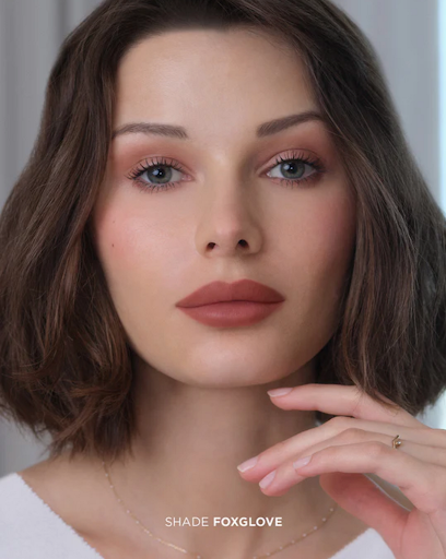 Close-up of a woman with brown hair, light skin, and light eyes wearing a nude lipstick color, showcasing beauty and fashion.