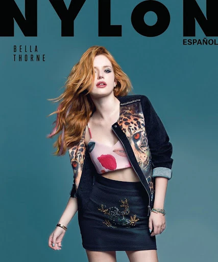 Magazine cover featuring Bella Thorne with red hair wearing a floral crop top, a jacket with tiger print, and a black skirt against a blue background.