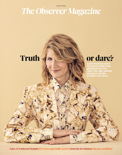 Portrait of Laura Dern with blonde hair wearing a patterned blazer against a solid cream background