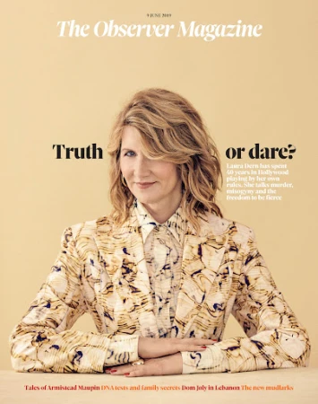 Portrait of Laura Dern with blonde hair wearing a patterned blazer against a solid cream background