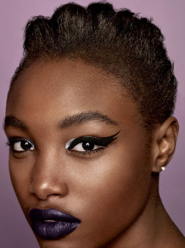 Close-up beauty portrait of a Black woman with bold graphic winged eyeliner and dark purple lipstick by makeup artist Lisa Houghton