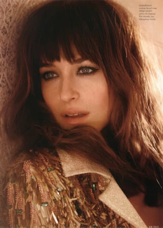 Close-up portrait of a woman with long brown hair and bangs wearing an embellished fringed coat with makeup by Lisa Houghton.